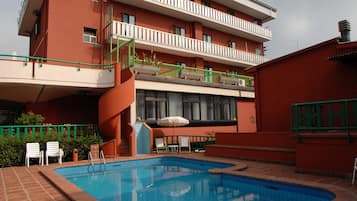 Alberca al aire libre, sombrillas en la alberca y camastros