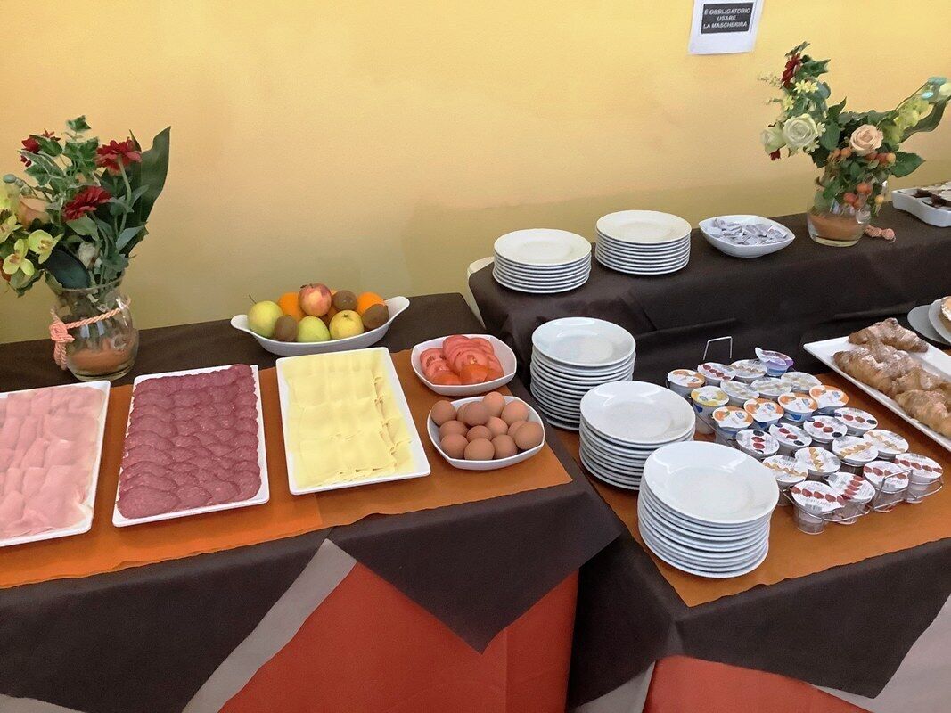 A buffet table with various food items and dishes, including fruits, eggs, and pastries, arranged on a table with a black tablecloth.