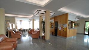 A spacious lobby with leather sofas, a reception desk, and a large plant. - La Querceta (Montecatini Terme)
