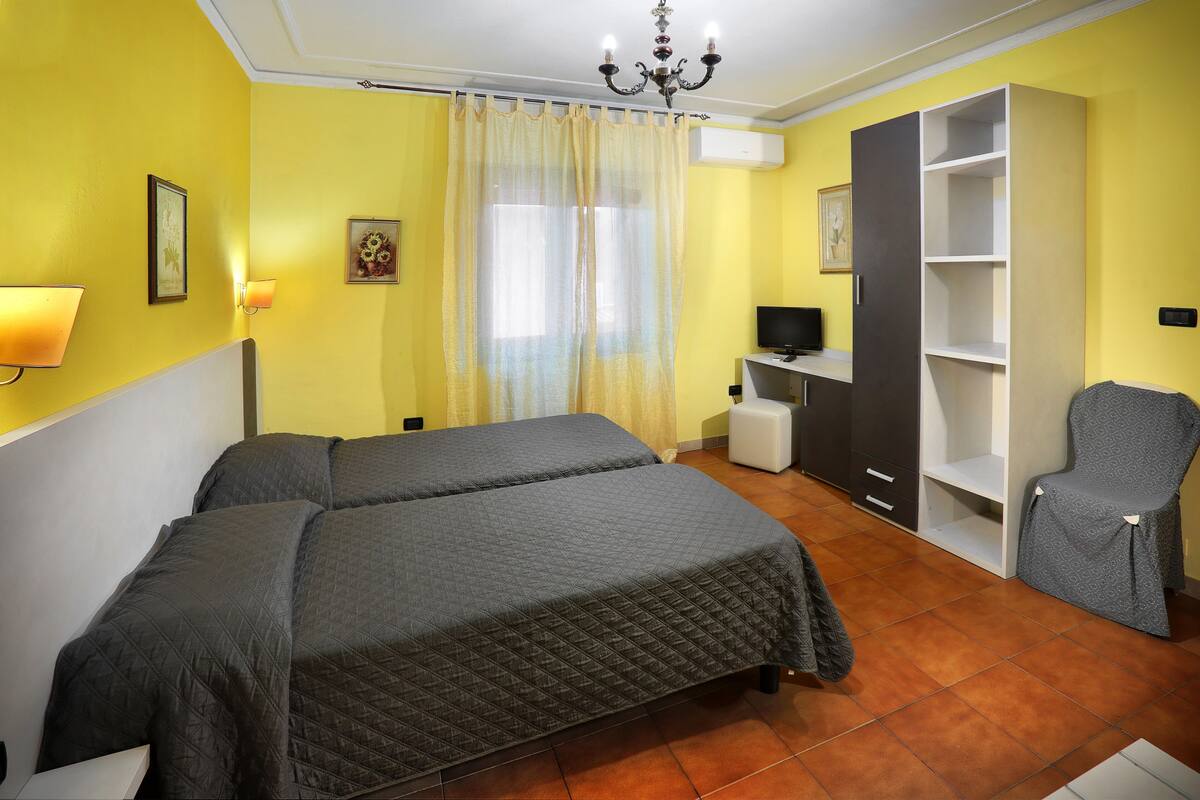A room with two beds, a desk, a chair, and a wardrobe.