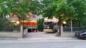 A building with a red facade, a covered entrance, and a parked bus in front. - La Querceta (Montecatini Terme)