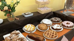 A table with various pastries and desserts, including cakes and pies, arranged on a tablecloth. - La Querceta (Montecatini Terme)