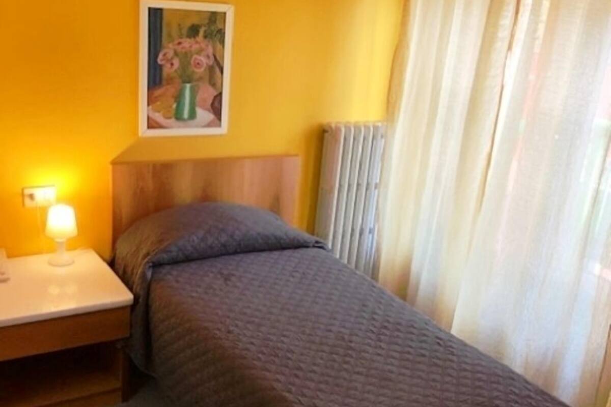 A single bed with a wooden headboard in a room with yellow walls.