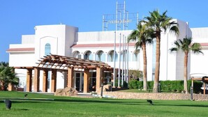 A resort with a white building, palm trees, and a covered outdoor area. - Cyrene Island Hotel (sharm el sheikh)