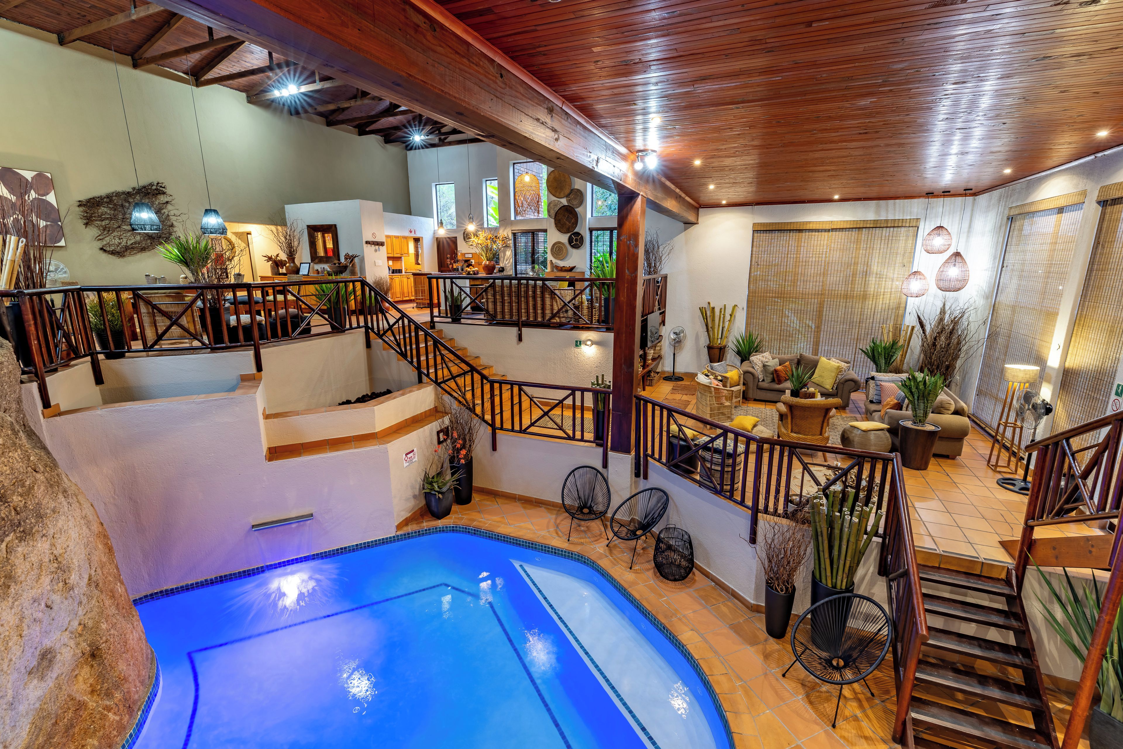 A multi-level indoor space with a swimming pool, wooden flooring, and a staircase.