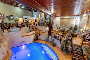 Un espacio interior de varios niveles con piscina, suelo de madera y una escalera.