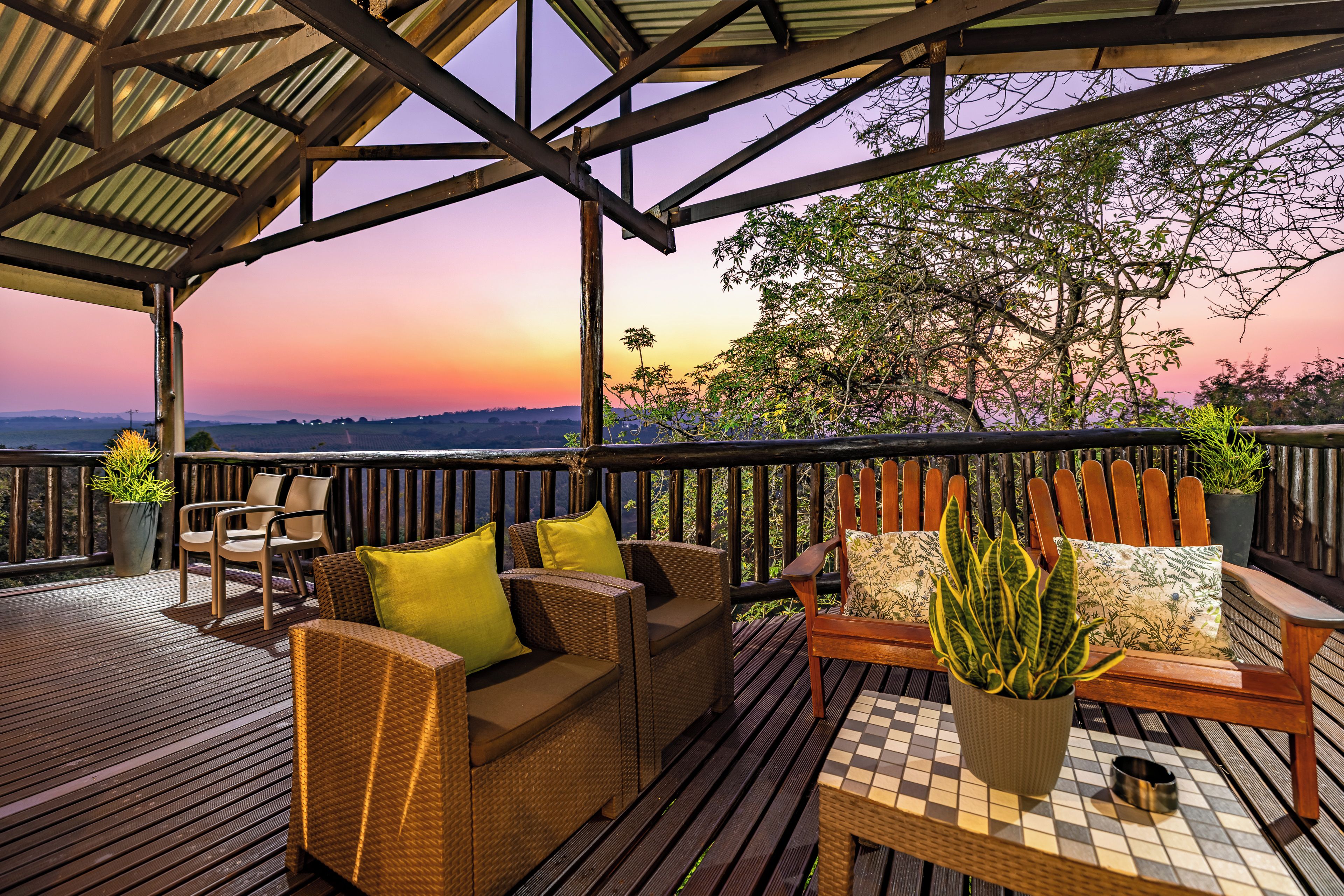 Une terrasse en bois, agrémentée de meubles en osier et de plantes en pot, qui offre une vue imprenable sur un paysage magnifique.