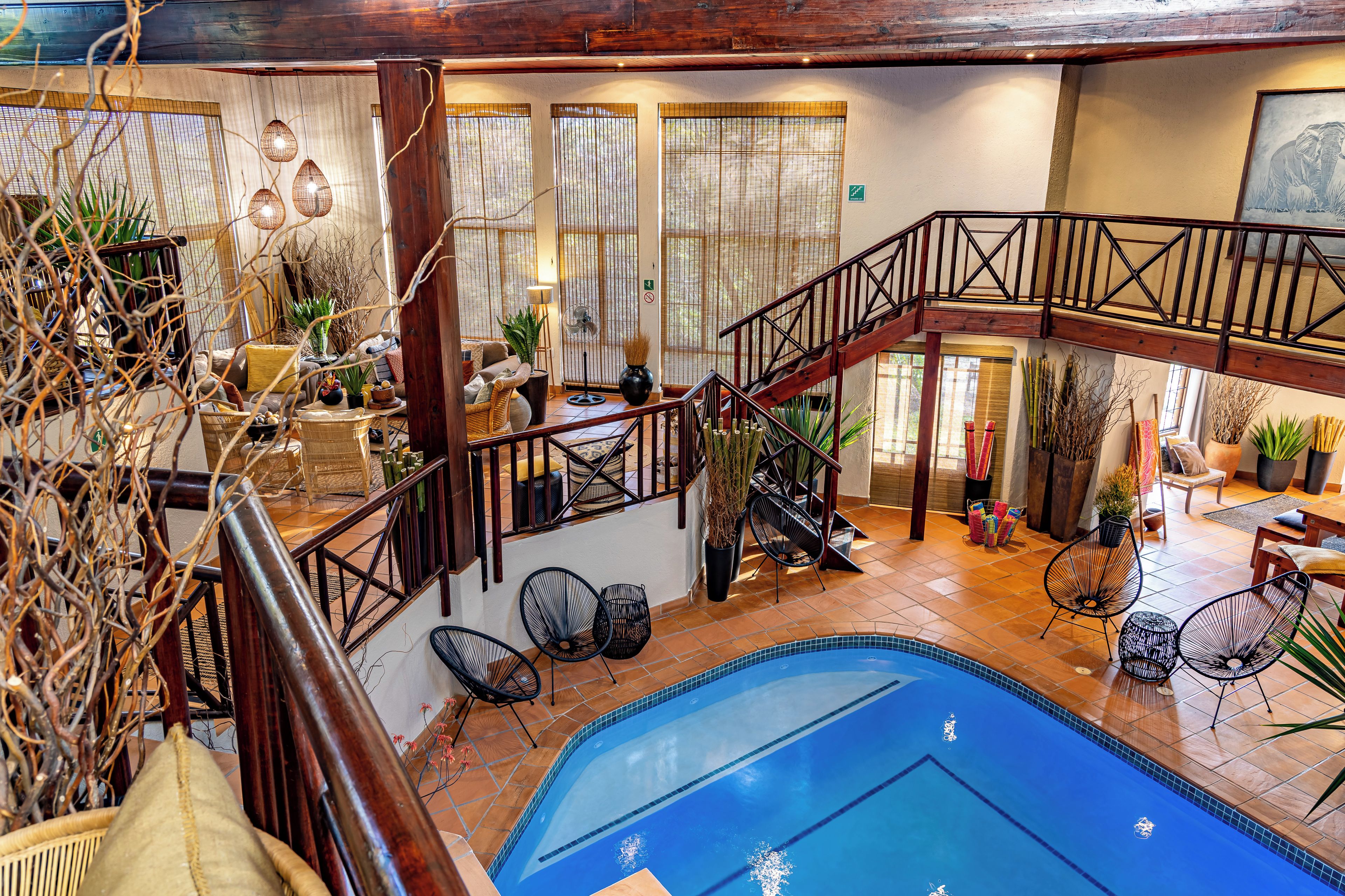 A spacious indoor area with a pool, wooden staircase, and various seating arrangements.