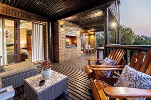 Une terrasse en bois avec des sièges d’extérieur, une cheminée et une vue sur le paysage environnant.