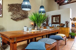 Una mesa de madera para comer con bancos, un jarrón con plantas verdes y un reloj de pared.