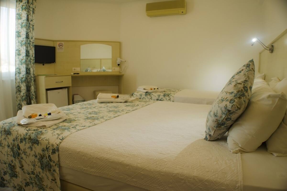 A hotel room with a bed, a desk, and a mirror.