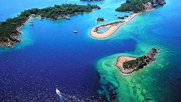Vista aérea de una zona costera con varias islas, aguas azules cristalinas y embarcaciones.