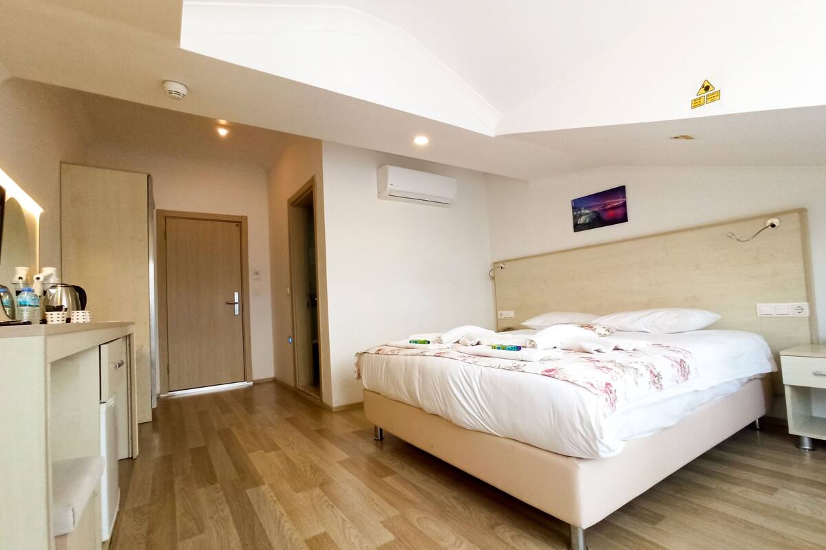 A hotel room with a bed, bedside table, and a mirror.