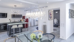 A modern kitchen with a central island, bar stools, a chandelier, and a Buddha statue. - Design-Studiowohnung in Gütersloh (Guetersloh)