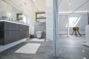 Une salle de bain moderne avec un grand miroir, des toilettes et un lavabo.