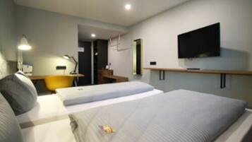 Habitación de hotel con dos camas, un escritorio, una silla, un televisor y una lámpara.