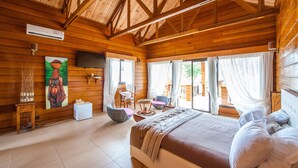 Un dormitori d'estil cabana de fusta amb un llit gran, una televisió i un quadre a la paret.