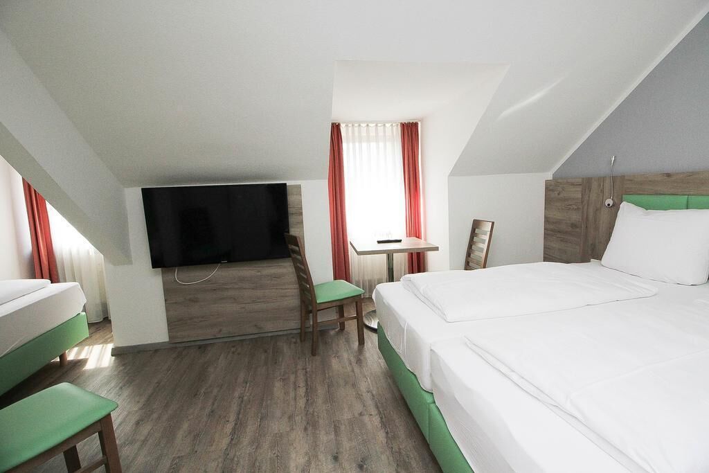 A hotel room with a bed, a desk, a chair, and a television.