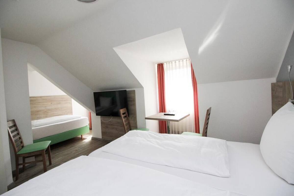 A modern hotel room with a loft bed, a small desk, and a television.