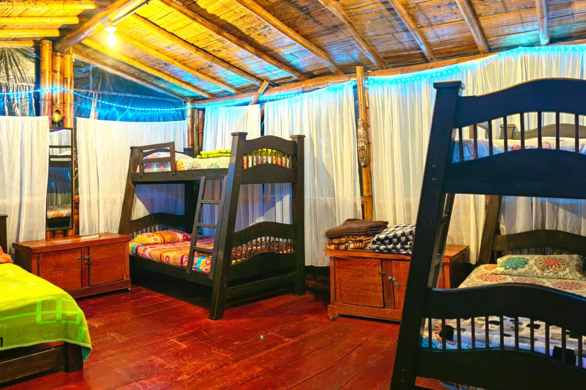 Une chambre rustique avec des lits superposés en bois, une armoire en bois et un lit recouvert d’une couverture verte.