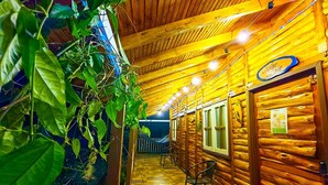 Ein Holzblockhaus-Innenraum mit Fliesenboden, einer Hängematte und einem kleinen Tisch.