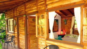 Eine Holzhütte mit einem Bett, einem Sessel und einem Tisch.