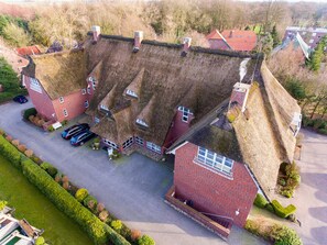 A large, uniquely shaped building with multiple roof sections, surrounded by well-maintained gardens and a parking area. - Hotel Graf Bentinck (Varel)