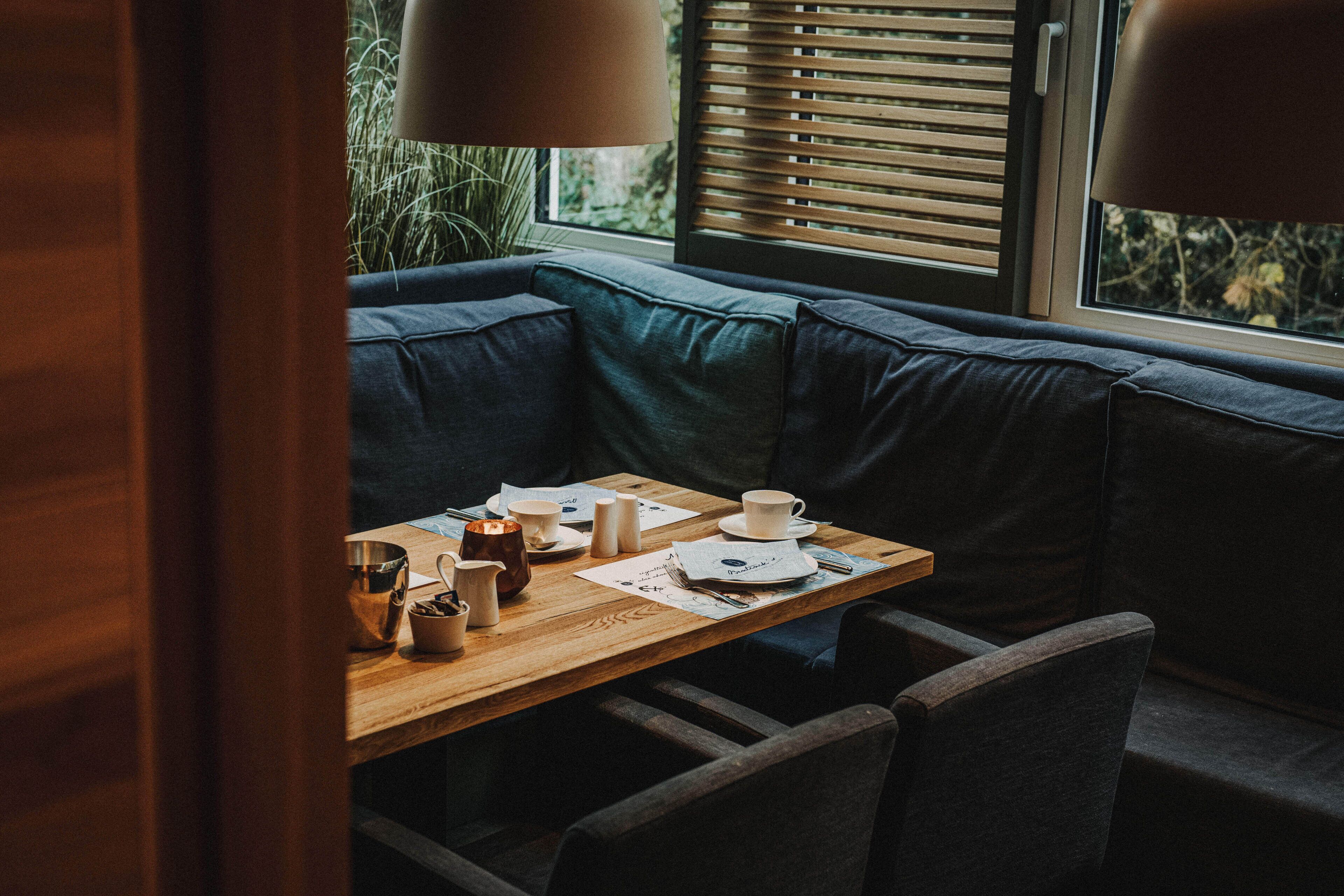 A cozy seating area with a wooden table, cushioned bench, and a window with blinds.