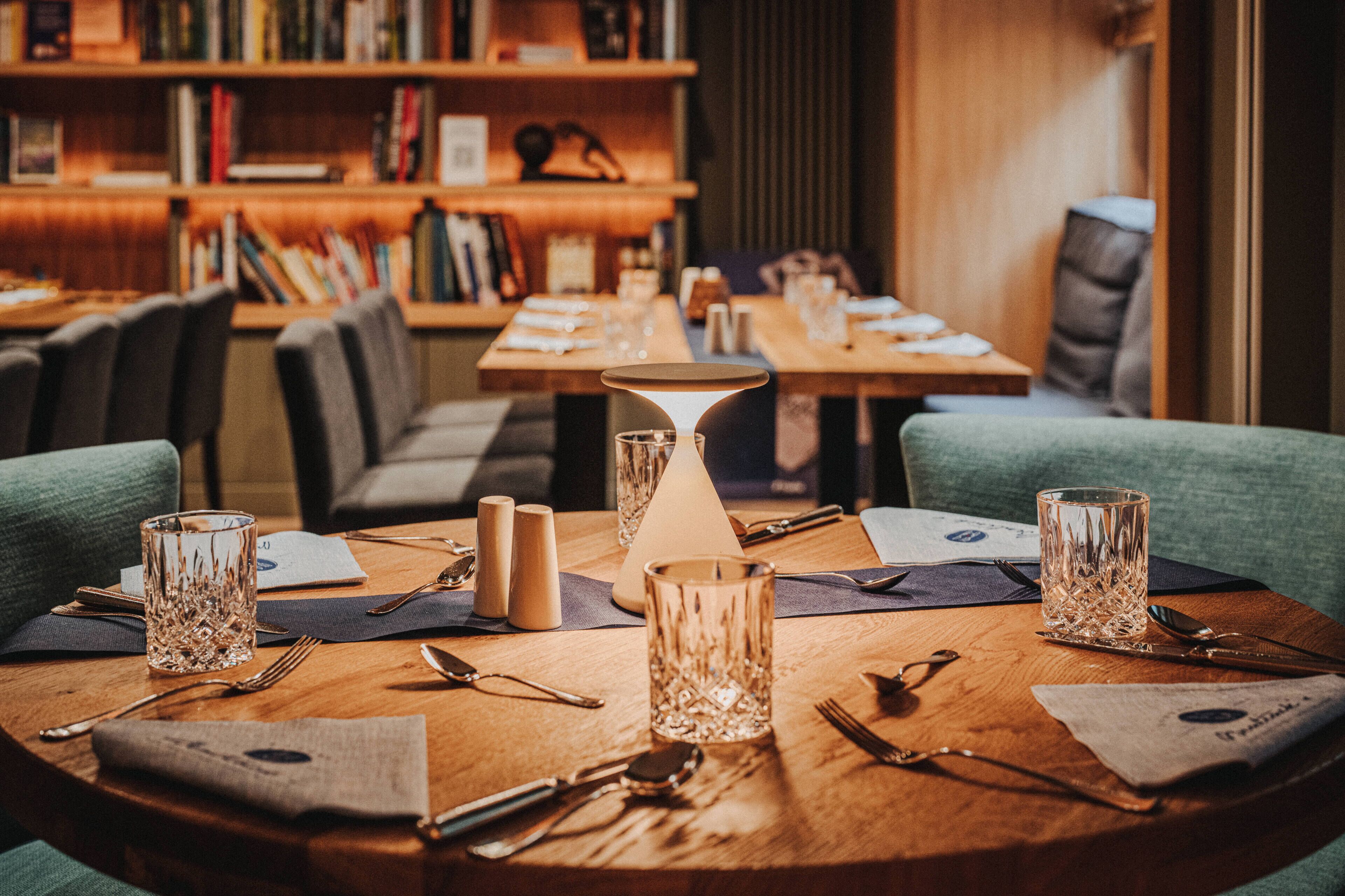 Una mesa de comedor con una lámpara, saleros y pimenteros, y una carta.