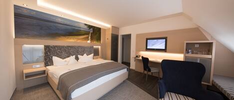 A modern hotel room with a large bed, a desk, a chair, and a TV.