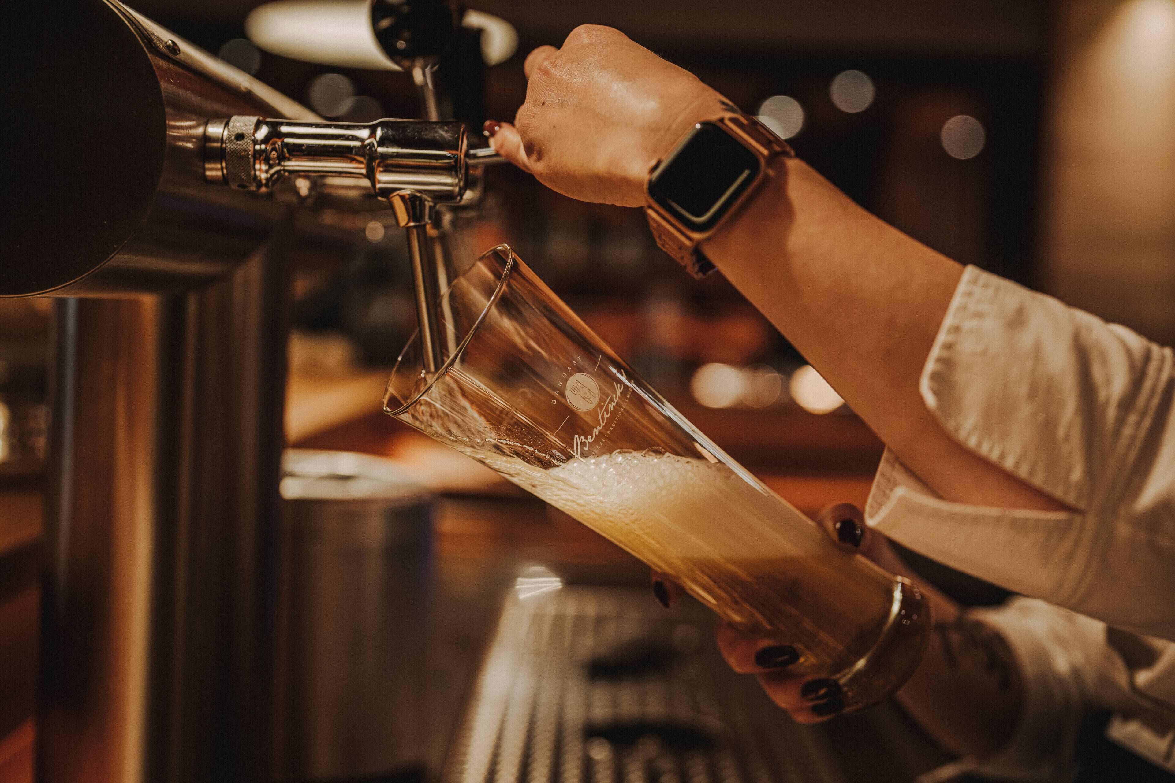 Une personne qui verse un liquide d’un robinet dans un verre.