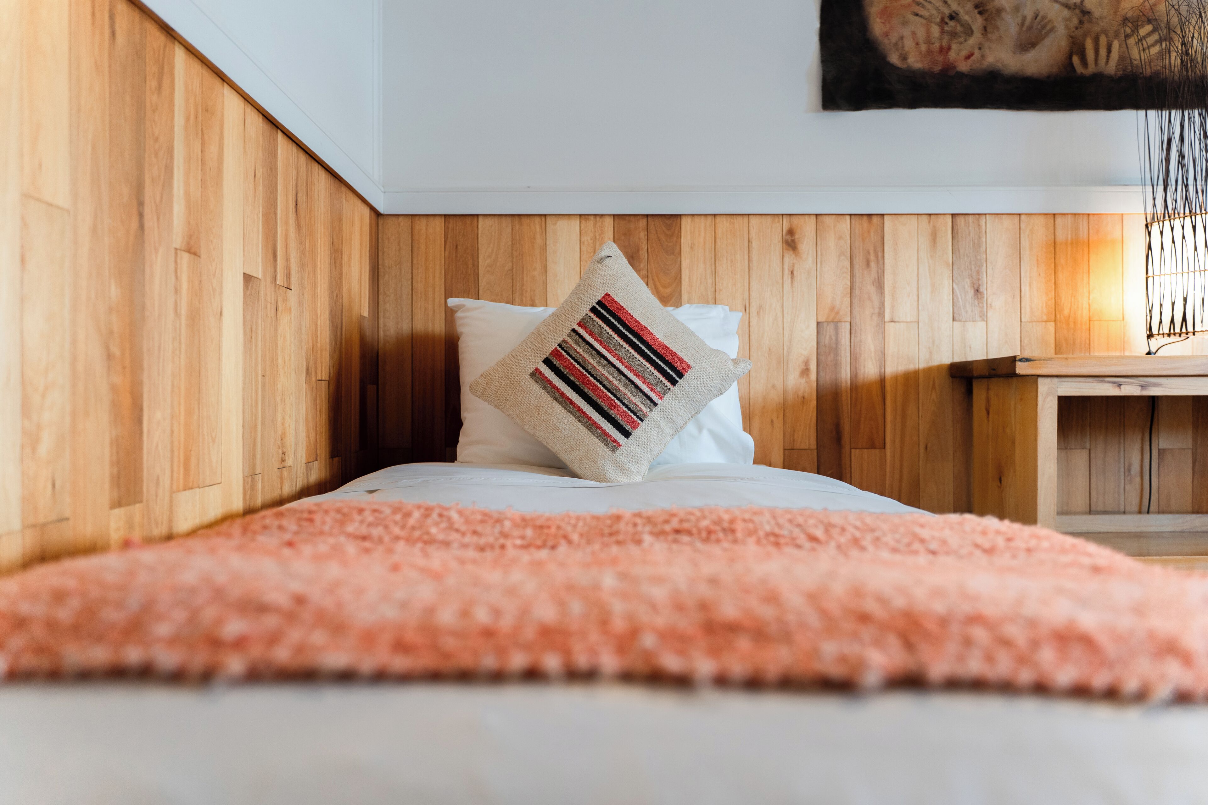 A bedroom with a wooden headboard, a pink fluffy rug, and a striped pillow.