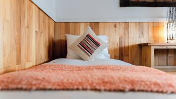 A bedroom with a wooden headboard, a pink fluffy rug, and a striped pillow.