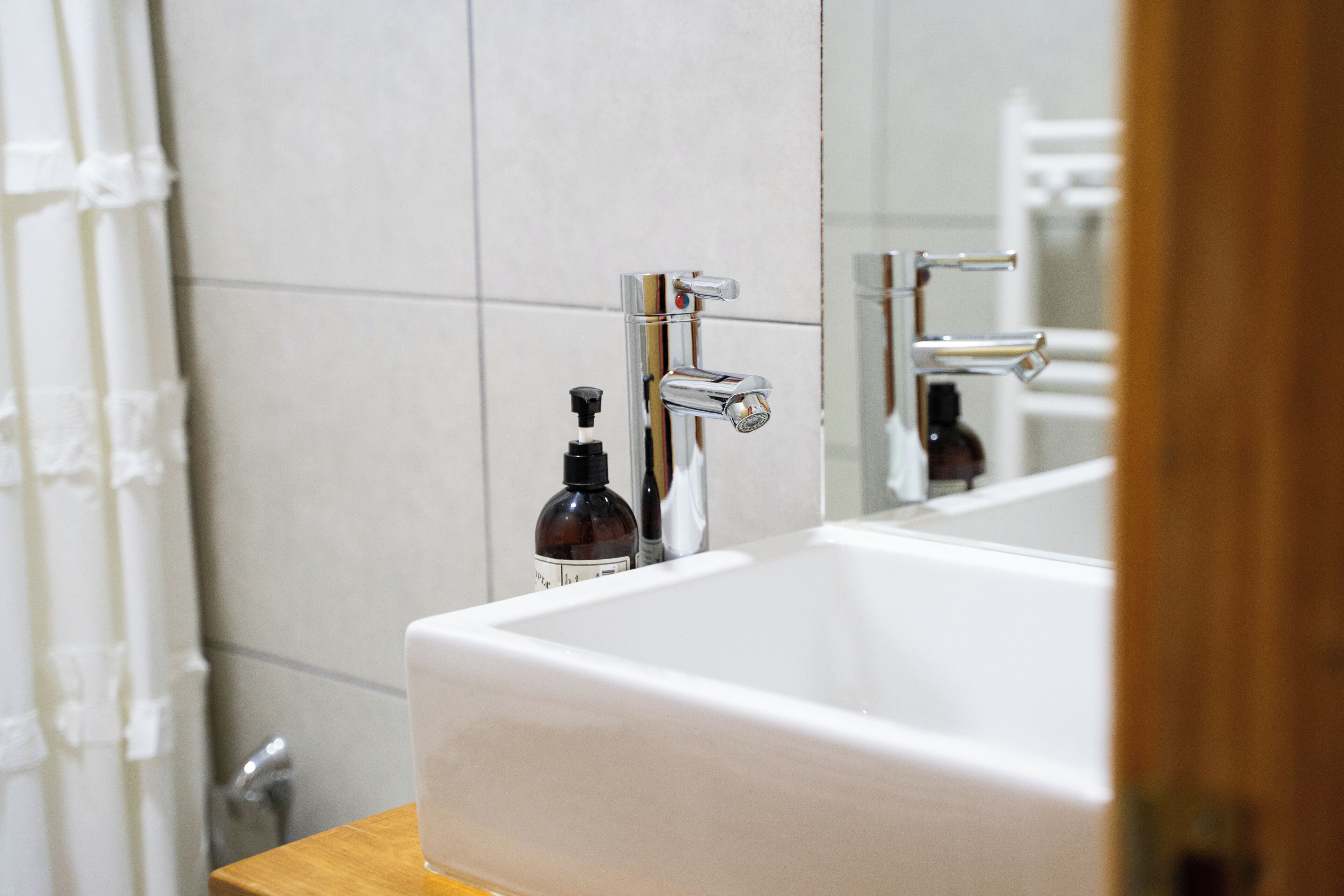 Un baño con una bañera blanca grande, grifos de cromo y un espejo que refleja la habitación.