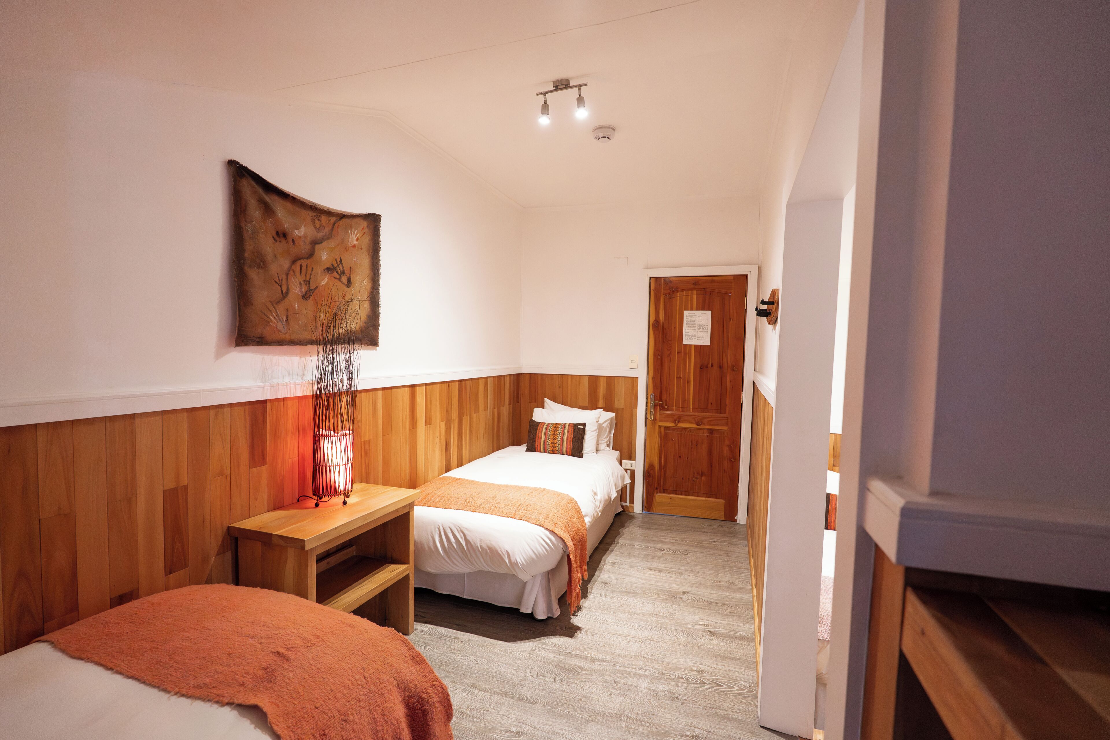 Un dormitorio con dos camas, cabecero de madera, una mesita de noche y una obra de arte colgada en la pared.