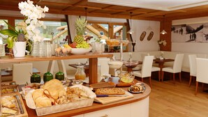 A breakfast buffet with various food items and a decorative orchid plant. - Garni Rautal B&B (Marebbe)