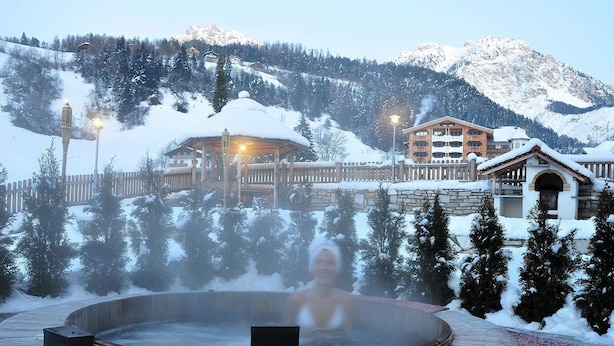 A hot tub surrounded by snow-covered trees and a mountainous backdrop. - Garni Rautal B&B (Marebbe)