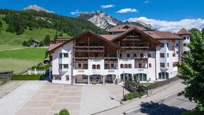 A large, multi-story hotel with balconies and a mountain backdrop. - Garni Rautal B&B (Marebbe)
