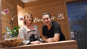 A wooden interior with a reception desk, a potted orchid, and a sign with the name "Benis". - Garni Rautal B&B (Marebbe)