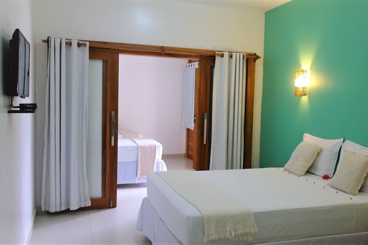 Un dormitorio con cama, televisión y una lámpara fijada a la pared.