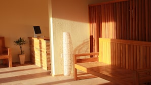 Un banco de madera, una mesita con una computadora portátil y una planta en maceta en un ambiente tipo spa.