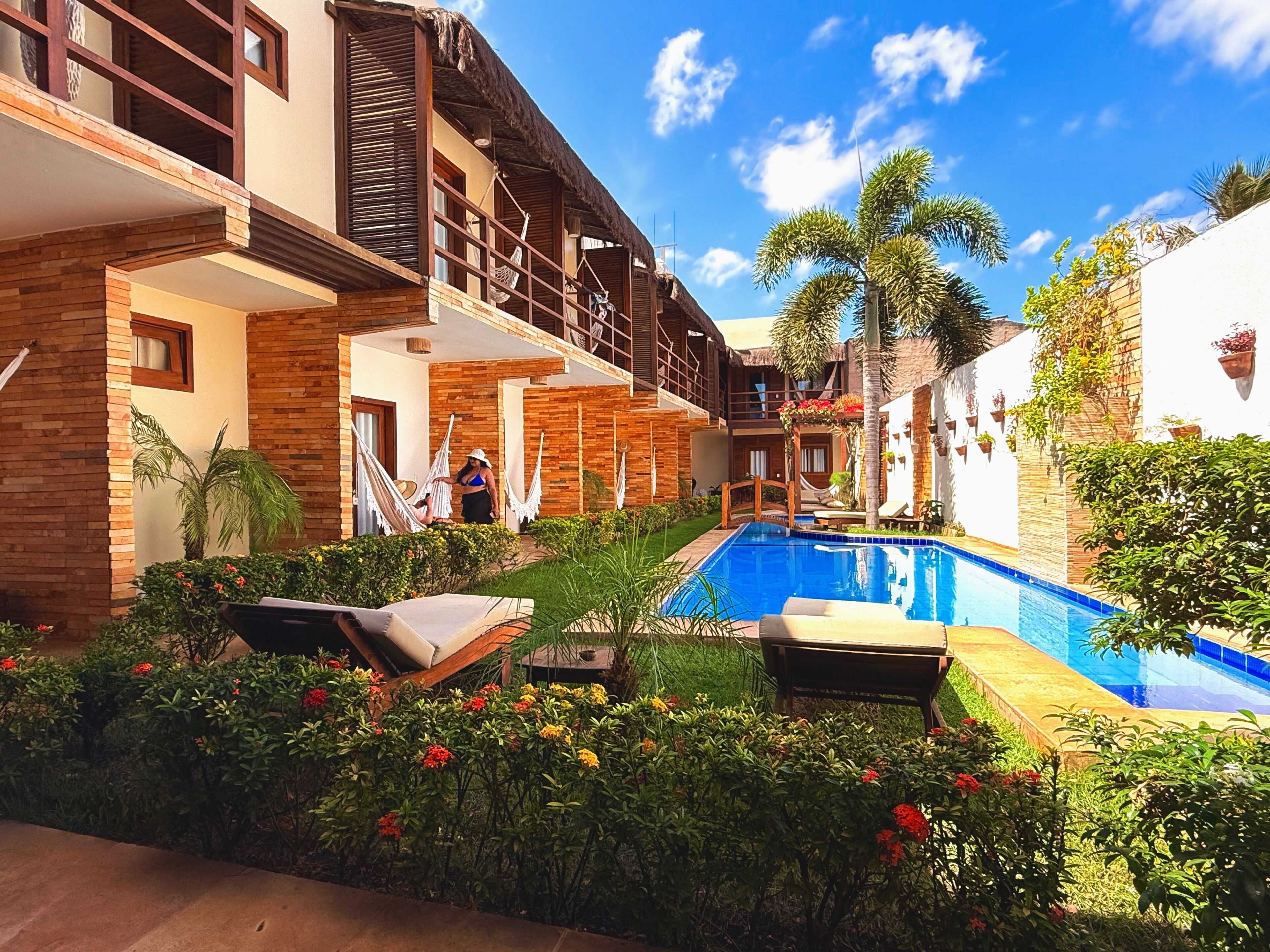 Zona junto a la piscina con piscina, sillas de descanso y una persona relajándose.