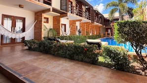 Un hotel con piscina, mobiliario exterior y una estructura de techo de paja.