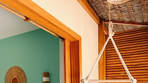 Una habitación con una cama, una puerta de madera, una hamaca colgada y un tapiz tejido en la pared.