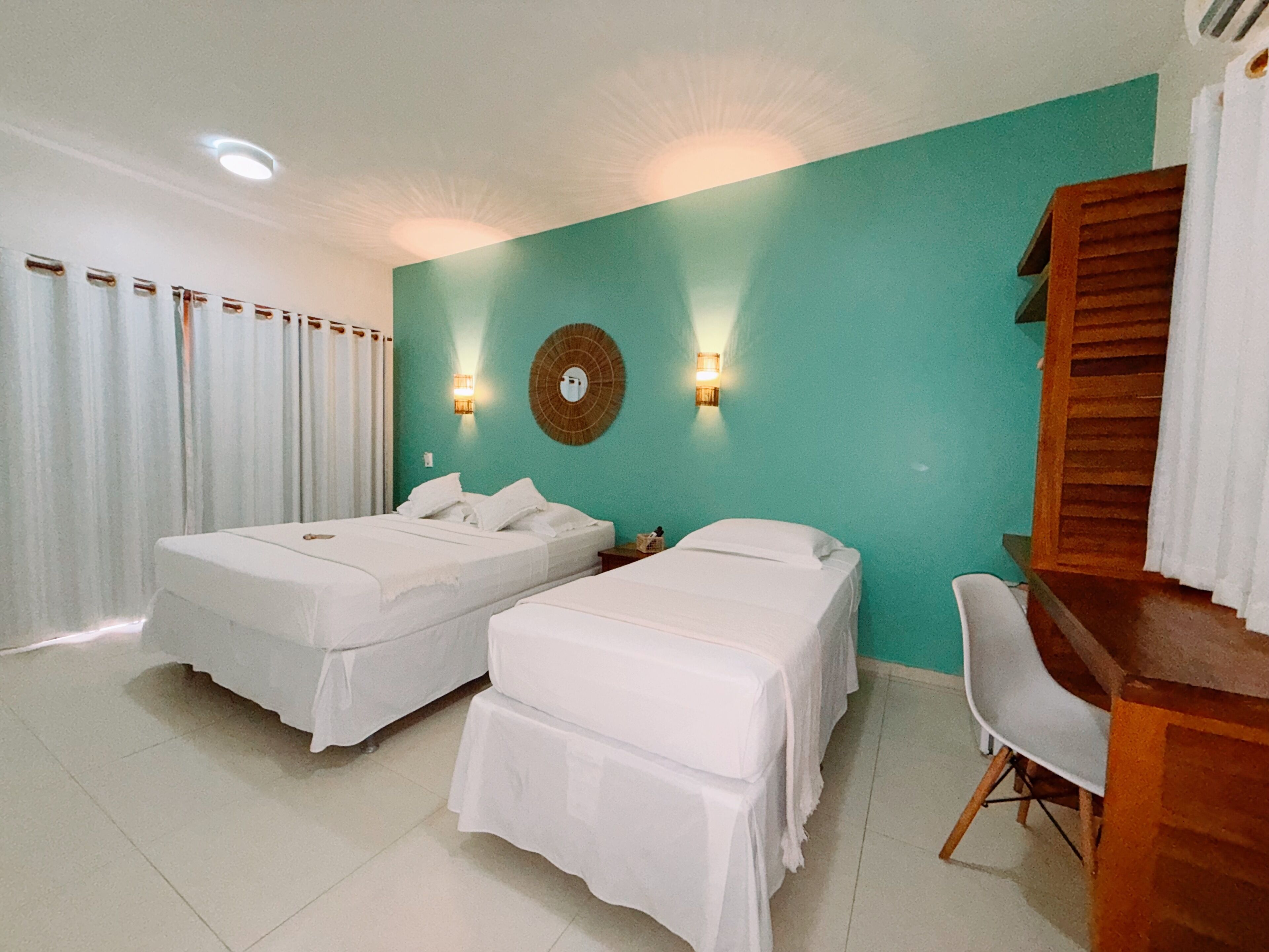 Habitación de hotel con dos camas, un escritorio, una silla y un espejo fijado a la pared.