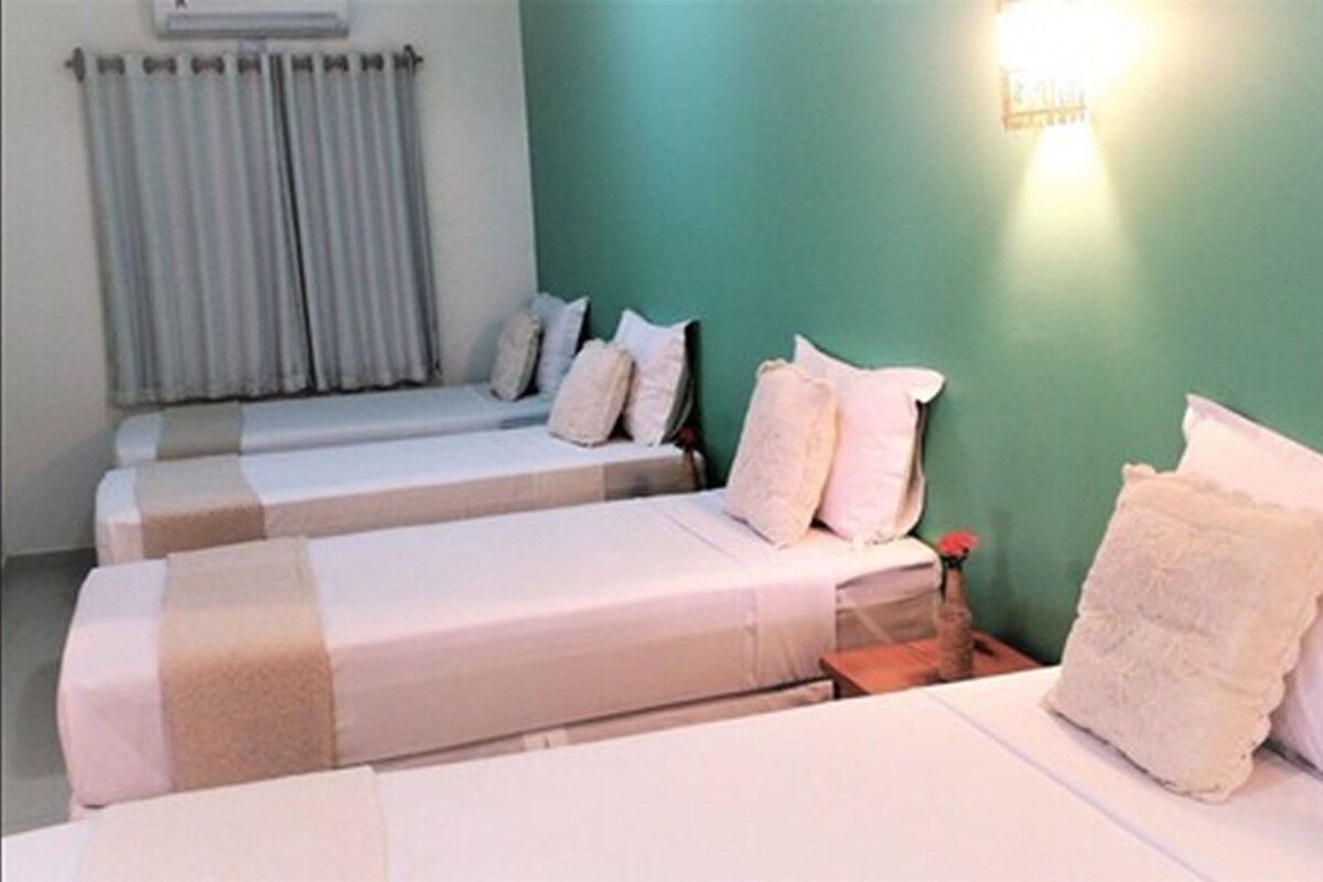 Una habitación con dos camas individuales, una mesita de noche con lámpara y una ventana con cortinas.