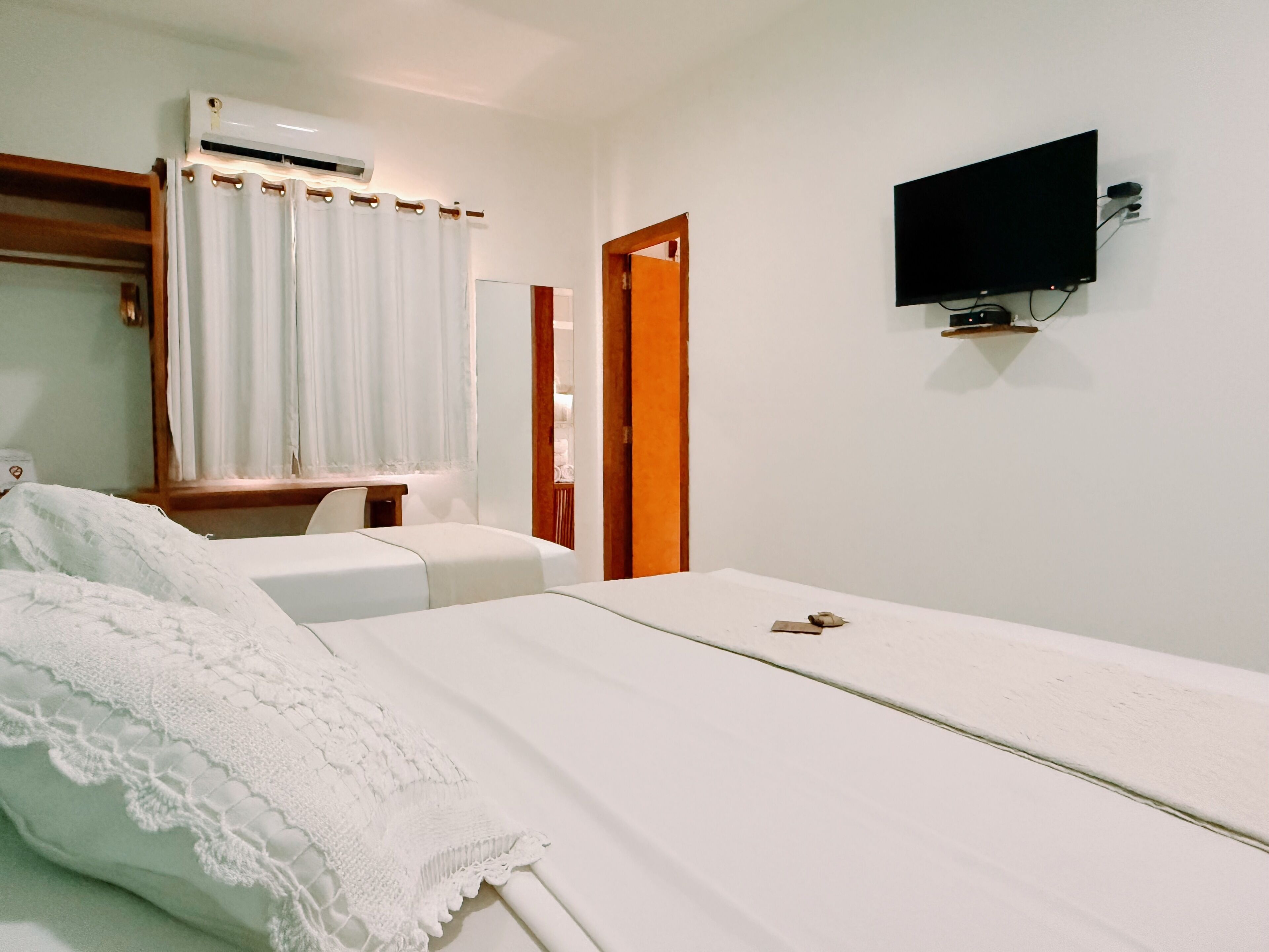 Una habitación de hotel con cama, escritorio, silla, aire acondicionado, televisión y puerta.
