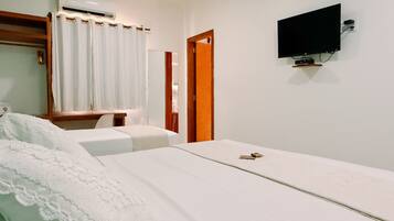 Una habitación de hotel con cama, escritorio, silla, aire acondicionado, televisión y puerta.