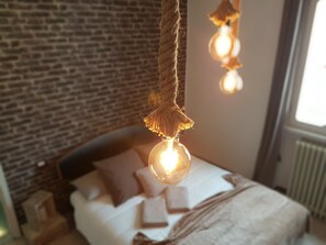 A bedroom with a brick wall, a bed with pillows, and hanging light fixtures. - Retro Apartment (Bergamo)