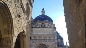 A historic building with a dome and clock tower, surrounded by tourists. - Retro Apartment (Bergamo)